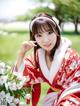 A woman in a red kimono holding a bunch of flowers.