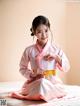 A woman in a pink hanbok sitting on a bed.