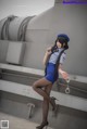 A woman in a blue dress and hat holding a gun.