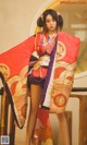 A woman in a red and purple kimono posing for a picture.