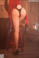 A woman in fishnet stockings and high heels sitting on a stool.