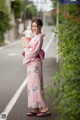 A woman in a pink kimono standing on the side of a road.