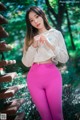 A woman in a white sweatshirt and pink leggings posing for a picture.
