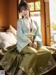 A woman in a green and blue hanbok sitting on a bed.