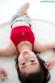 A young girl laying on a white rug with her hands on her stomach.