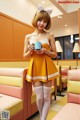 A woman in a yellow dress holding a cup of coffee.