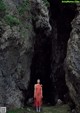 A woman in a red dress standing in a cave.