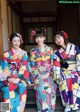 A group of three women in colorful kimonos sitting on steps.